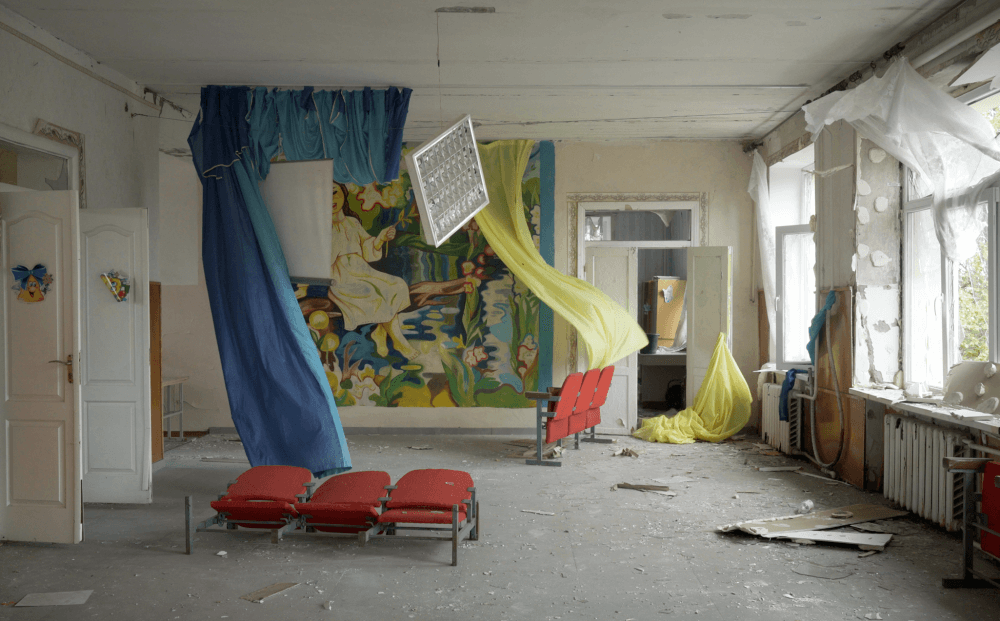 A cluttered room with a mural on one wall