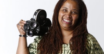 Headshot of Zeinabu irene Davis holding a camera and smiling